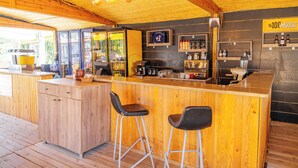 A wooden bar area with stools, a coffee machine, and shelves with bottles. - Assos Villa Natura (Ayvacik)