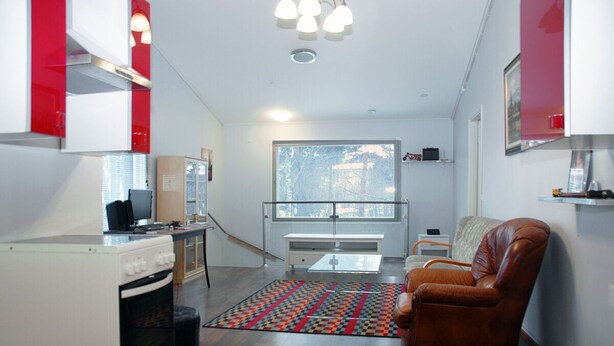 Un ambiente compatto con angolo cottura, divano, tappeto decorato e una grande finestra con vista.