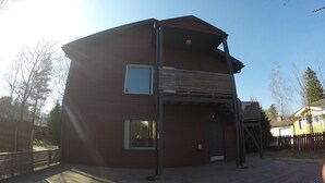 Una casa a due piani con una veranda in legno e un'area esterna coperta.