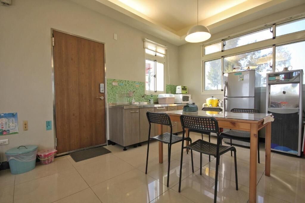 A kitchen with a wooden table and chairs, a refrigerator, a microwave, and a window with a view.