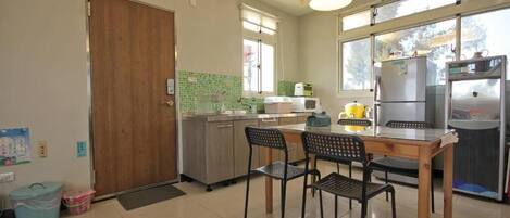 Una cocina con mesa y sillas de madera, un refrigerador, un microondas y un ventanal con vistas.