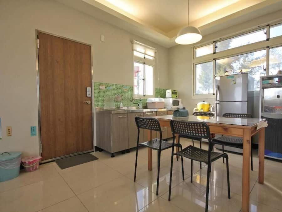 Una cocina con mesa y sillas de madera, un refrigerador, un microondas y un ventanal con vistas.