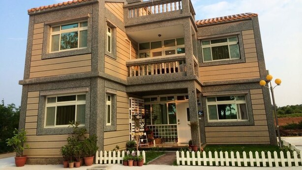 A multi-story building with a balcony, a water tank on the roof, and a white picket fence in the front. - Happy Tree Hostel (Jinning)