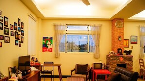 A cozy living room with a fireplace, a dining area, and a wall decorated with framed photos. - Happy Tree Hostel (Jinning)