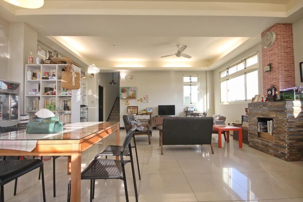 A spacious living area with a dining table, chairs, a sofa, a fireplace, and a television.