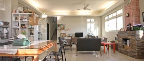 Un amplio salón con mesa de comedor, sillas, sofá, chimenea y televisor.