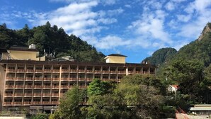 A multi-story hotel with balconies, surrounded by lush greenery and mountains. - Ku Kuan Hotspring Hotel (Taichung)