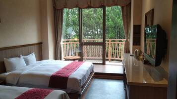 A hotel room with two beds, a balcony with a wooden railing, a television, and a small table.