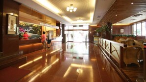 A hotel lobby with a reception desk, a waiting area with wicker chairs, and a patterned ceiling. - Ku Kuan Hotspring Hotel (Taichung)