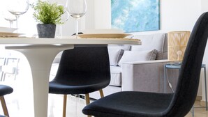 Ein stilvoller Essbereich mit einem weißen Tisch, schwarzen Stühlen und einem grauen Sofa.