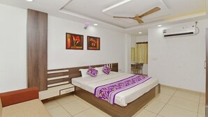 A modern bedroom with a bed, a nightstand, a chair, and a ceiling fan. - Hotel Jaishree Palace (Bhopal)
