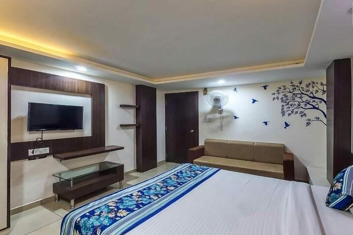 Een slaapkamer met een bed, een aan de muur bevestigde televisie, een ventilator en een decoratief wandobject.