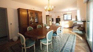 Una sala da pranzo con un tavolo e sedie in legno, un lampadario e un mobiletto con vetrate.