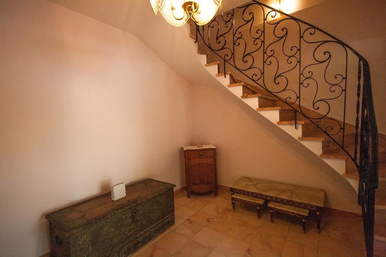 A staircase with ornate metal railings, a wooden bench, and a small cabinet.