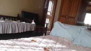 Un dormitorio con dos camas, un armario de madera y una ventana con rejas.
