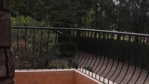 Una zona de patio con baldosas, un diseño floral geométrico, una barandilla de metal y un muro de piedra.