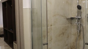 Una ducha con cerramiento de vidrio, cabezal de ducha de mano y grifo empotrado en la pared.