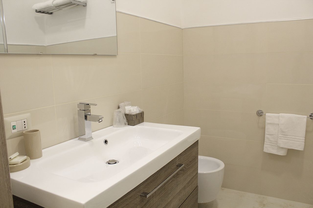 A modern bathroom with a white sink, a mirror, and a toilet.