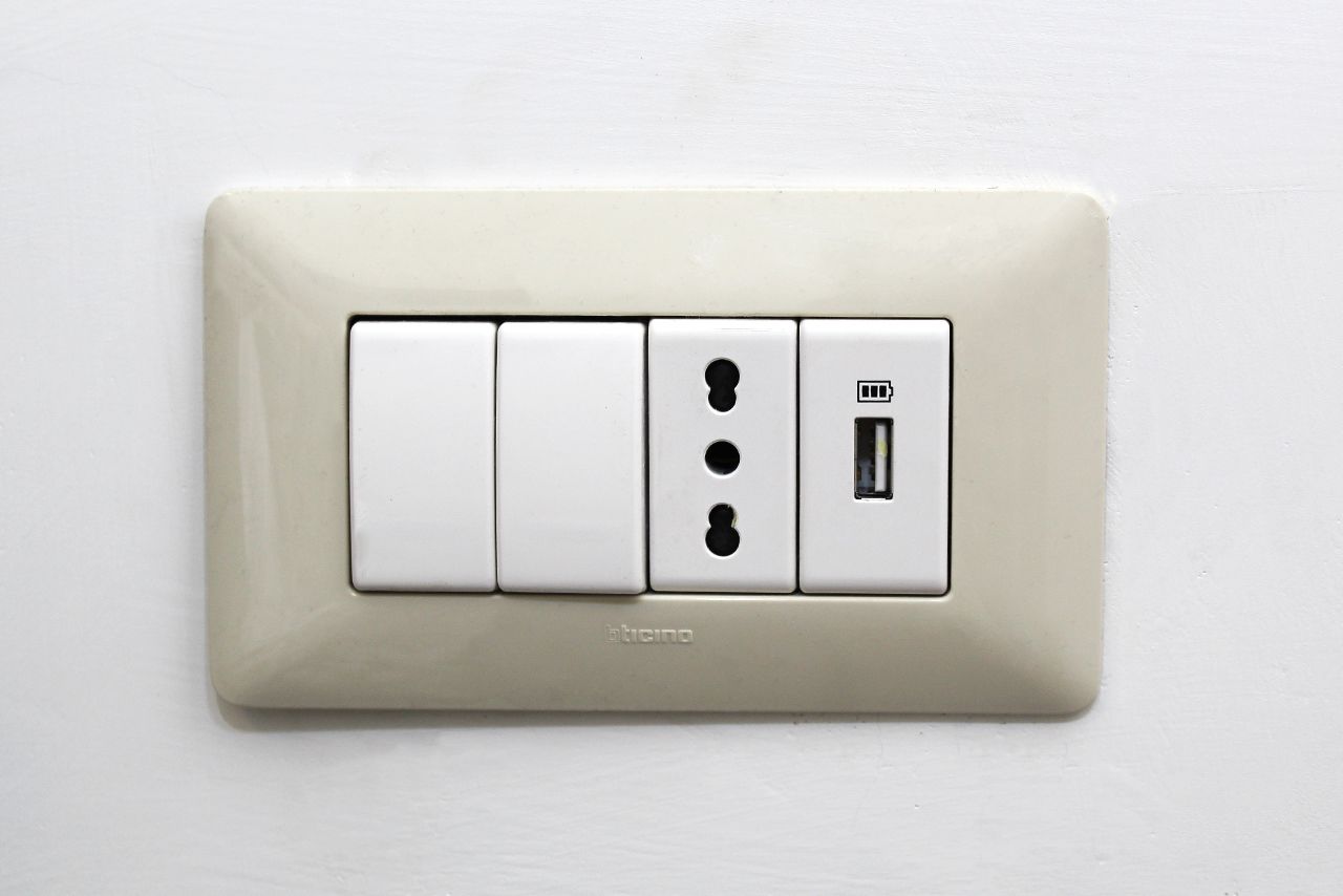 A wall-mounted electrical outlet with three switches and a USB port.