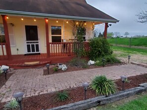 A house with a porch, a small garden, and a brick pathway.