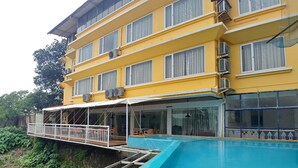 A multi-story yellow building with a swimming pool, outdoor seating, and air conditioning units. - Lake View Resort (Mawal)