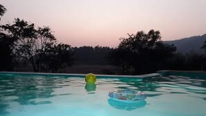 A swimming pool with clear water, surrounded by trees and a hilly landscape in the background. - Lake View Resort (Mawal)