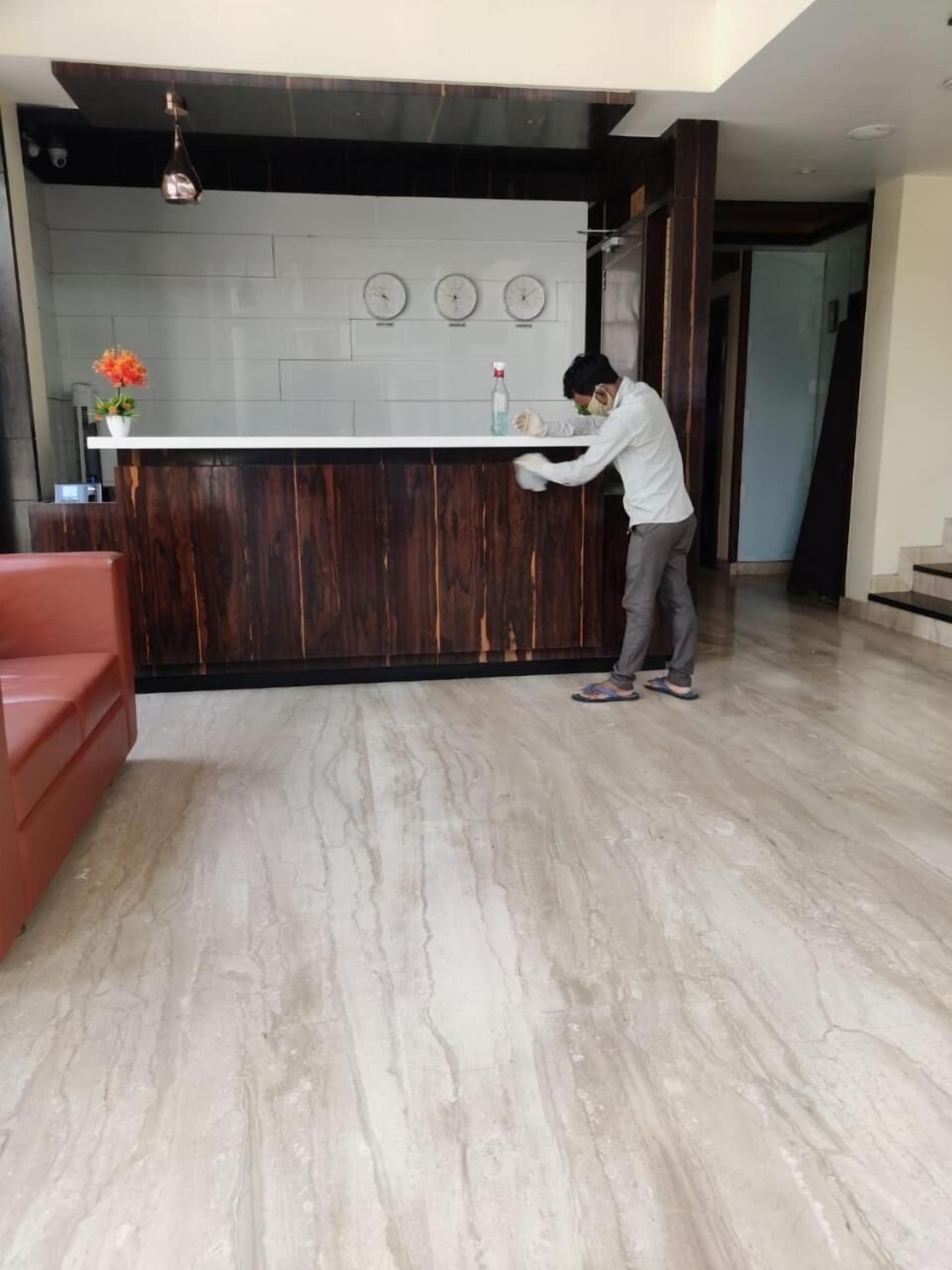 A reception area with a wooden reception desk, a red sofa, and a marble floor.
