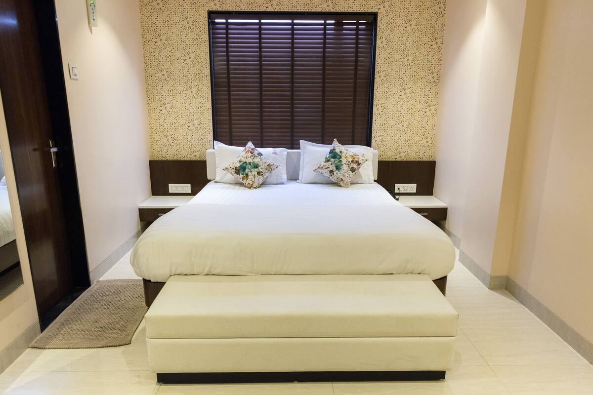 A neatly arranged bedroom with a large bed, two bedside tables, and a bench at the foot of the bed.