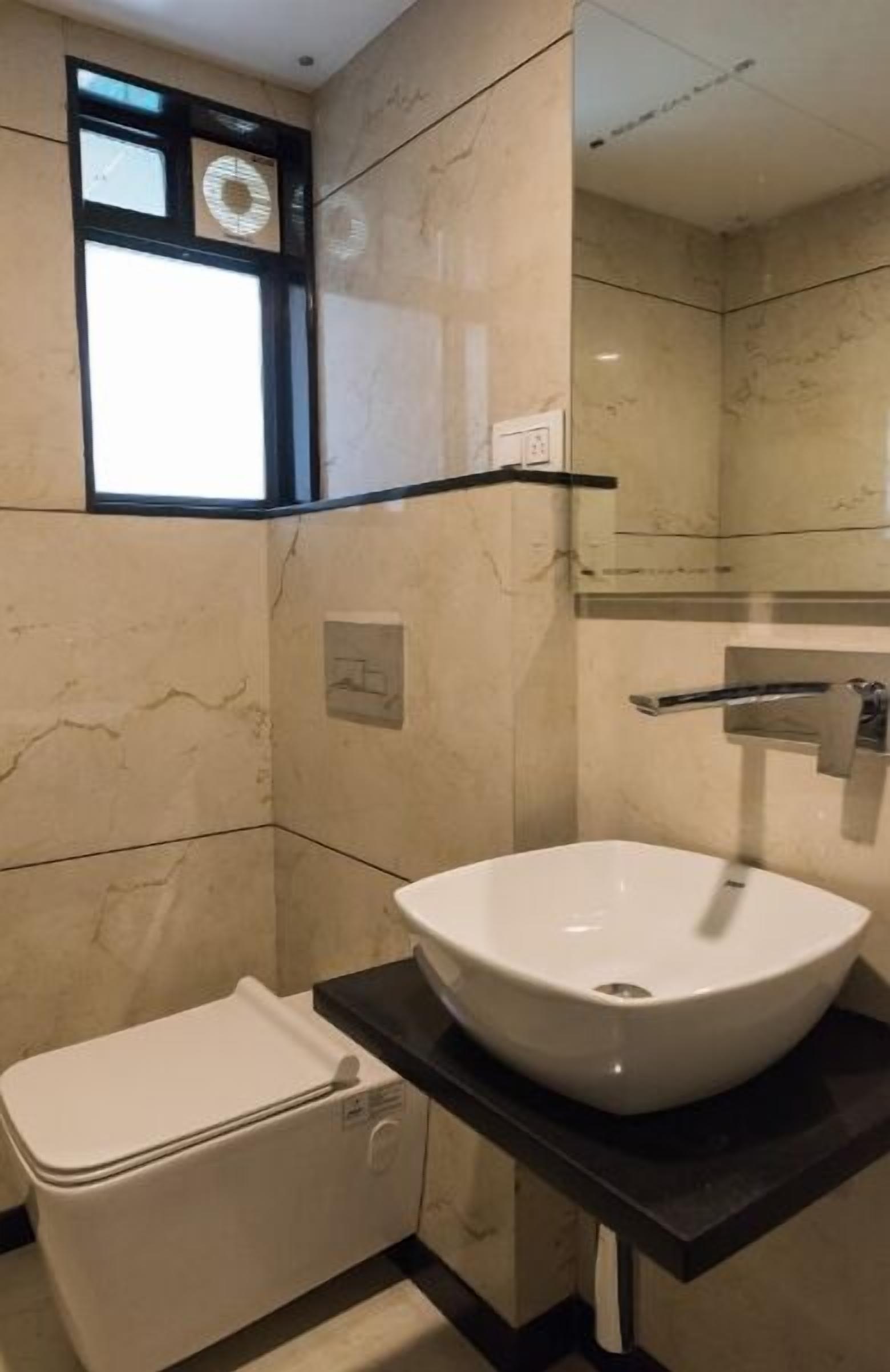 A bathroom with a white toilet, a large white sink, and a mirror above the sink.