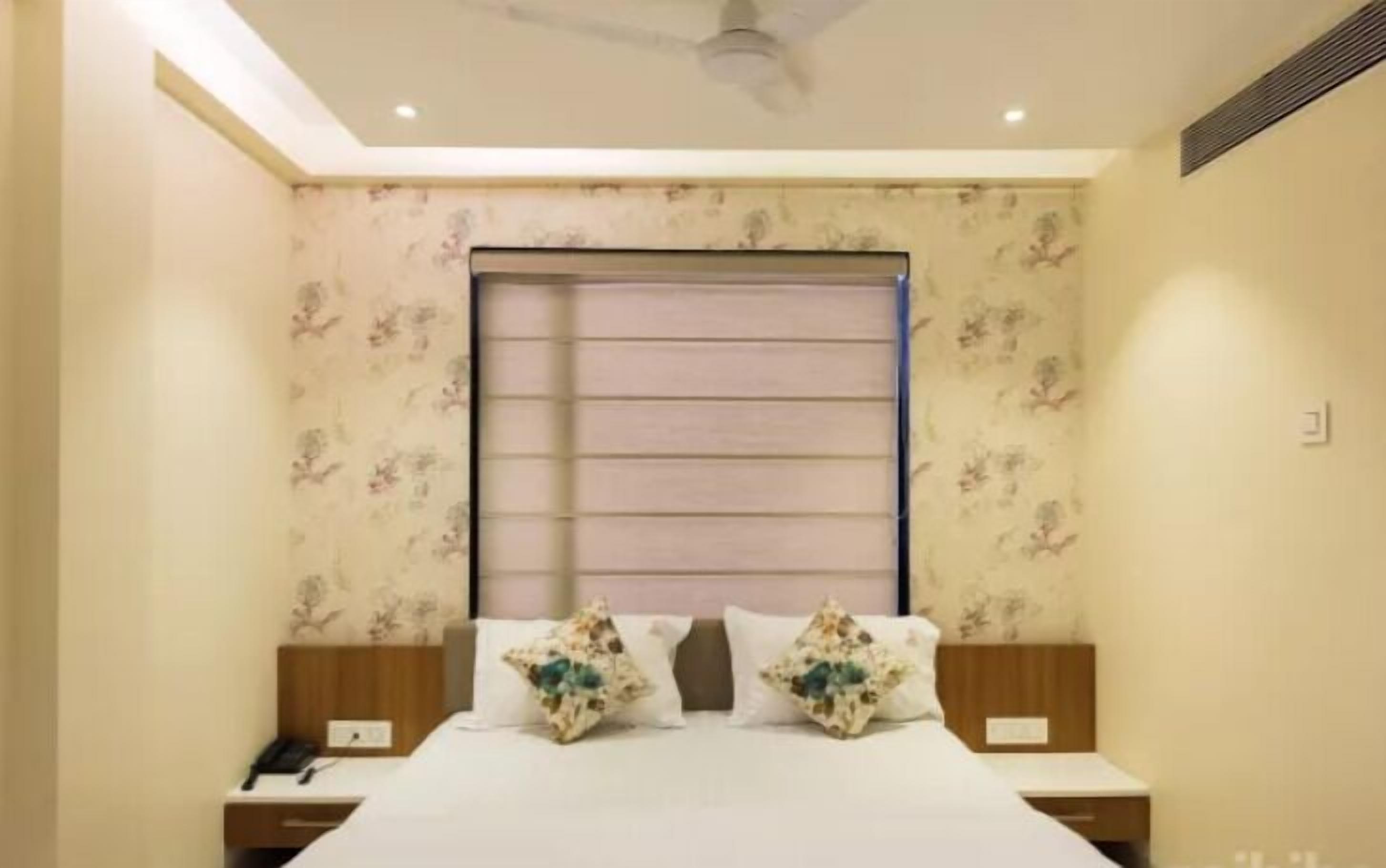 Ein Schlafzimmer mit einem Bett, zwei Nachttischen, einem Deckenventilator und einem Fenster mit Jalousien.
