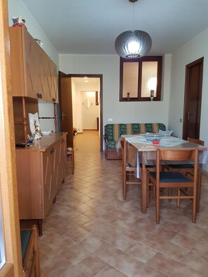Uma área de refeições com mesa e cadeiras de madeira, um sofá e um armário com gavetas.