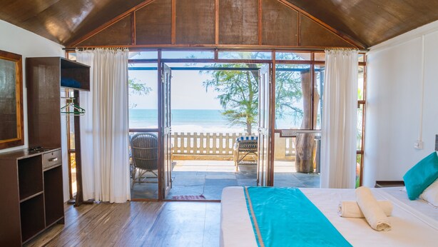 A room with a bed, a desk, and a view of the beach. - Peace Garden Goa (Canacona)