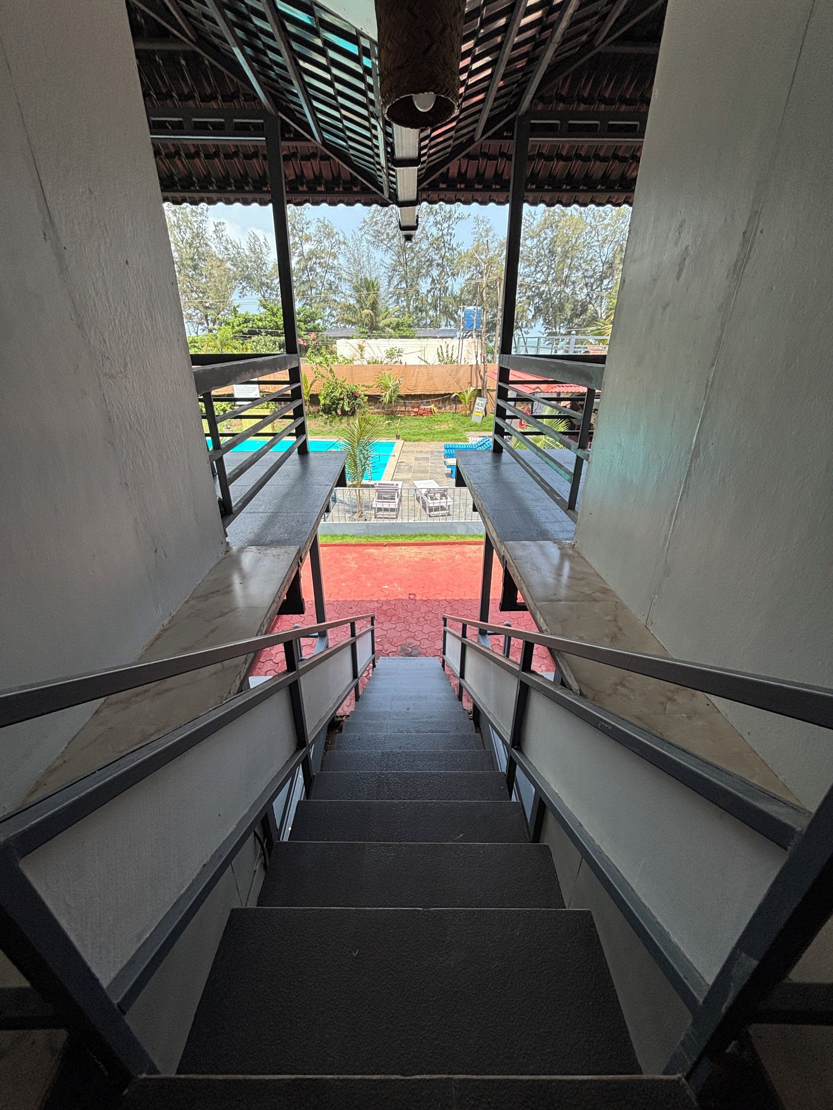 Una escalera conduce a un espacio exterior con piscina y zona de estar cubierta.