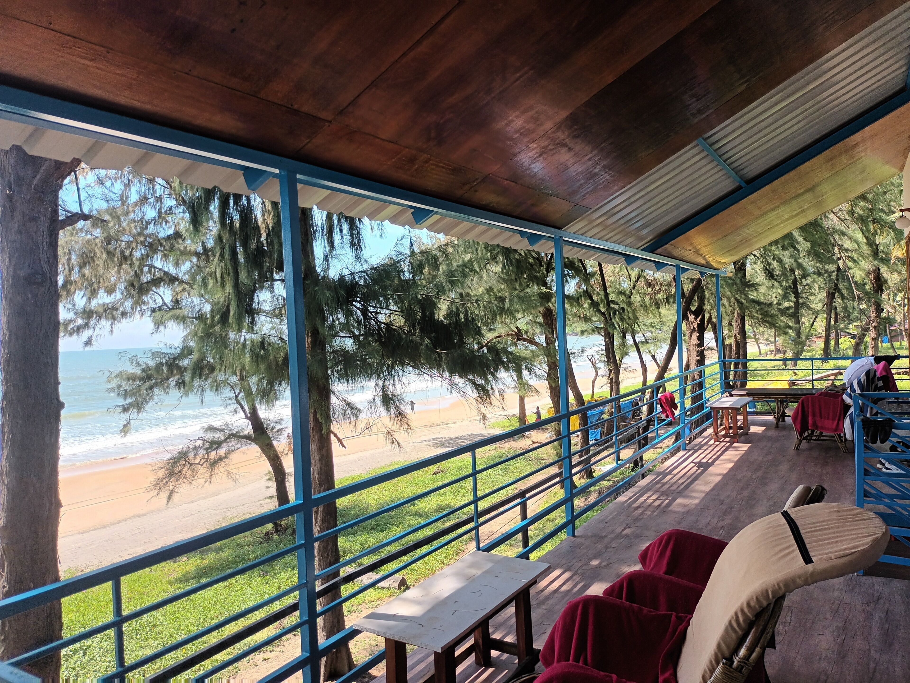 A covered outdoor seating area with a view of the beach and ocean.
