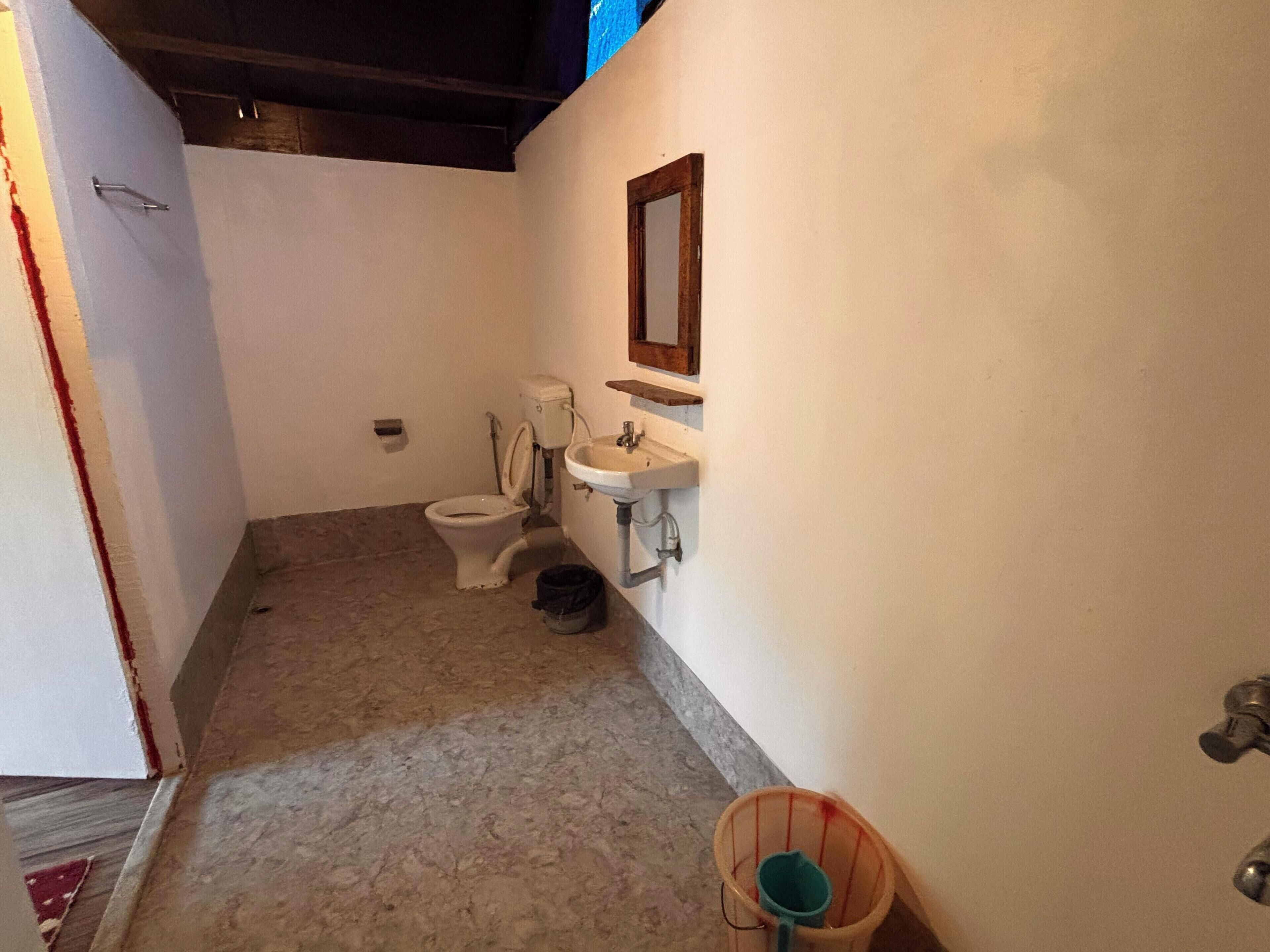 Un baño pequeño y funcional con inodoro, lavamanos y un pequeño cubo de basura.