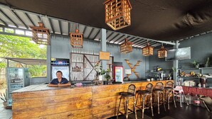 A bar area with wooden counter and chairs, a Pepsi sign, and a Coca-Cola refrigerator. - Peace Garden Goa (Canacona)