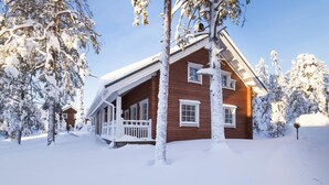 En træhytte med veranda omgivet af sneklædte træer.