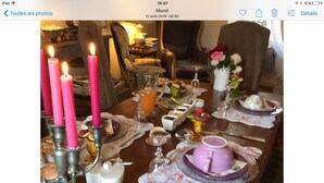 Une table à manger dressée avec des bougies, une théière et différents plats.