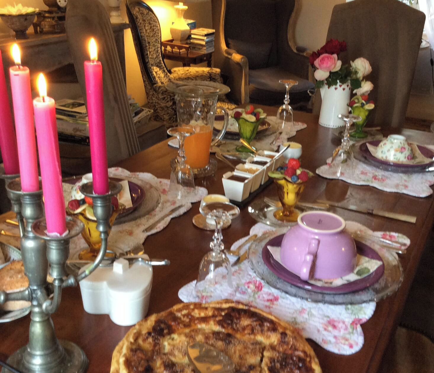 Une table à manger décorée avec des bougies roses, une variété de plats et un arrangement floral.