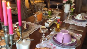 Une table à manger décorée avec des bougies roses, une variété de plats et un arrangement floral.