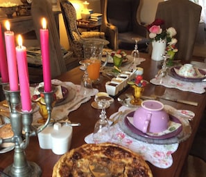 Une table à manger décorée avec des bougies roses, une variété de plats et un arrangement floral.