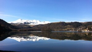 Un lac paisible, avec une montagne enneigée en arrière-plan, entouré de collines boisées.