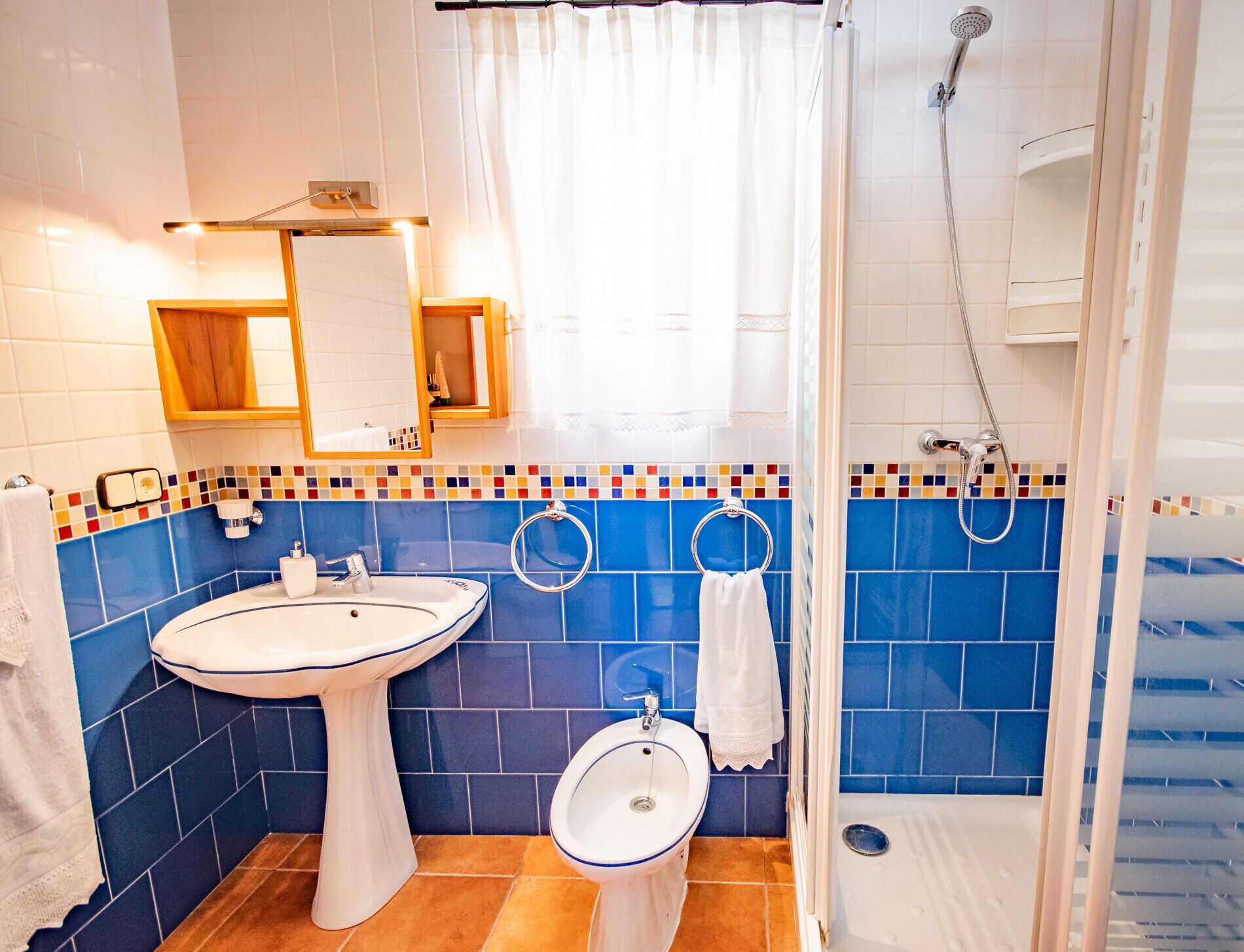 A bathroom with a pedestal sink, a toilet, and a shower stall.