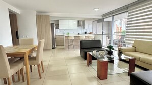 A modern living room with a dining area, a sofa, a coffee table, and a TV. - El Poblado! 2hab+Studio+Balcony+ parking, AC, fast WIFI, The Best in Medellin! (Medellín)
