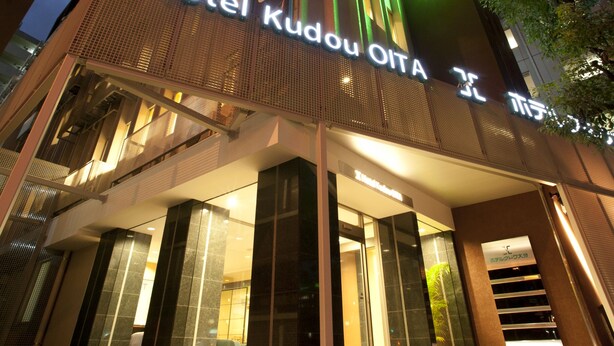 Hotel Kudou OITA -moderni julkisivu, suuri lasinen sisäänkäynti ja valaistut opasteet.