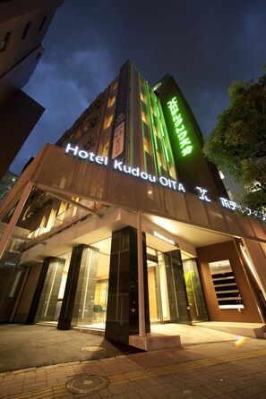 Hotel Kudou OITA met een moderne gevel, een ruime glazen entree en verlichte borden.