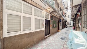 A narrow alleyway with a row of closed shops on one side and a parked motorcycle on the other. - HoHo Woo Tainan Homestay (Tainan)