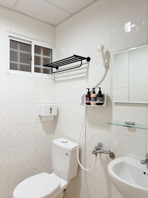 A bathroom with a toilet, a sink, a glass shelf with toiletries, a towel rack, and a window with frosted glass. - HoHo Woo Tainan Homestay (Tainan)