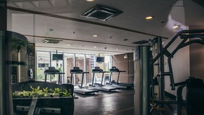Un gimnàs amb cintes de córrer, aparells de musculació i un gran finestral.