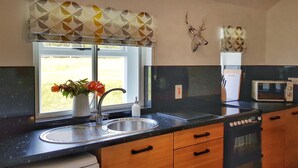 A kitchen with a sink, a microwave, and a window with a view of the outdoors. - The Corner Cottage Sandwick (Sandwick)